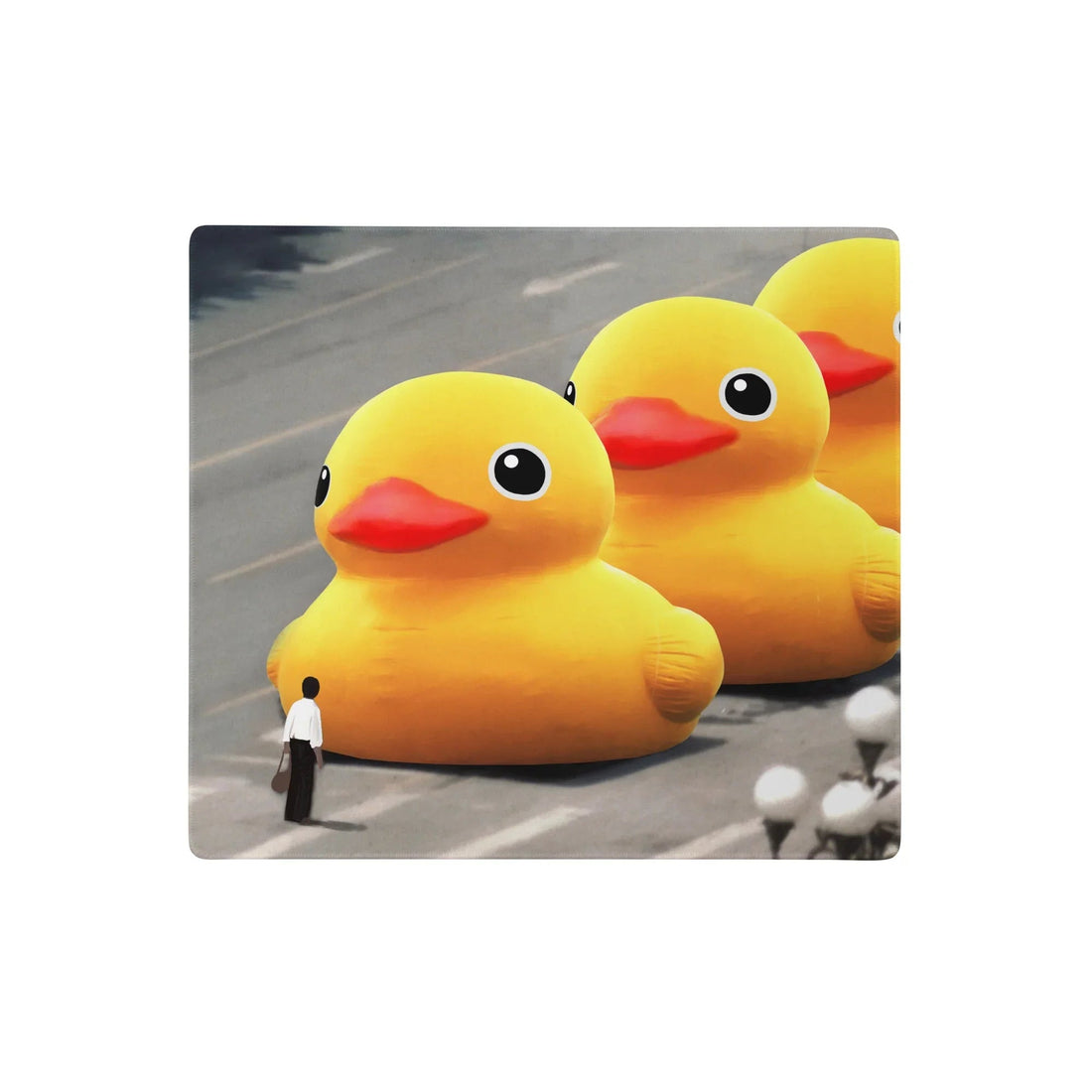 A satirical digital illustration depicts a solitary figure in white shirt and dark trousers facing down three colossal dandelion yellow rubber ducks (with tangerine beaks and black eyes) on a wide urban avenue. Contact us with accessibility feedback, we'd love to help!